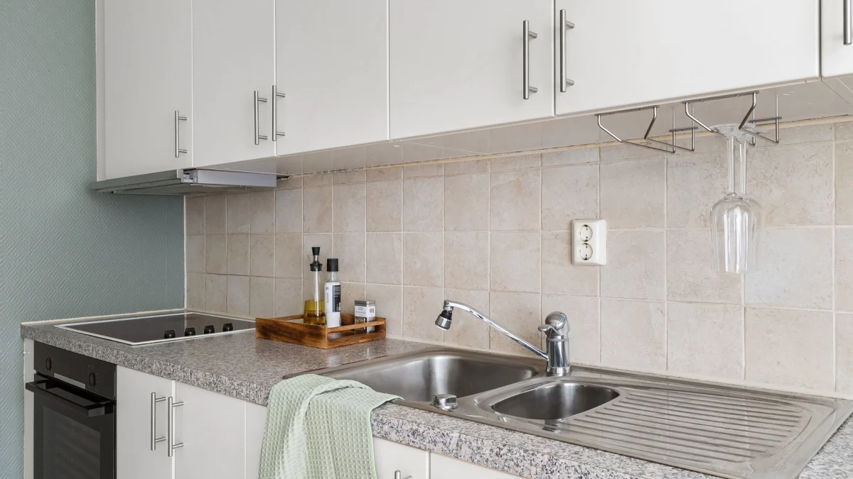 Stijlvolle moderne keuken met granieten werkblad, roestvrijstalen gootsteen en witte kasten.